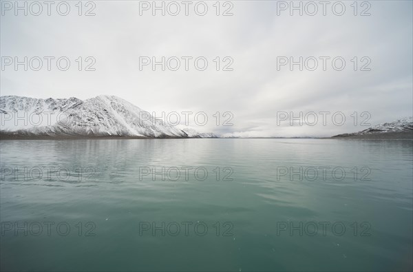 Turquoise-coloured sea in front of snow-covered mountains