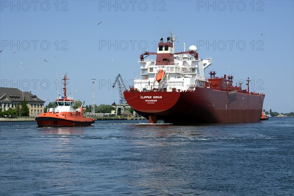 A cargo ship is towed from the Gdansk shipyard by a tug boat