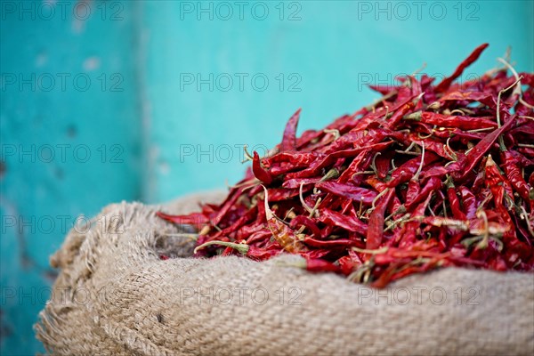 Red chillies in a sack against a turquoise wall