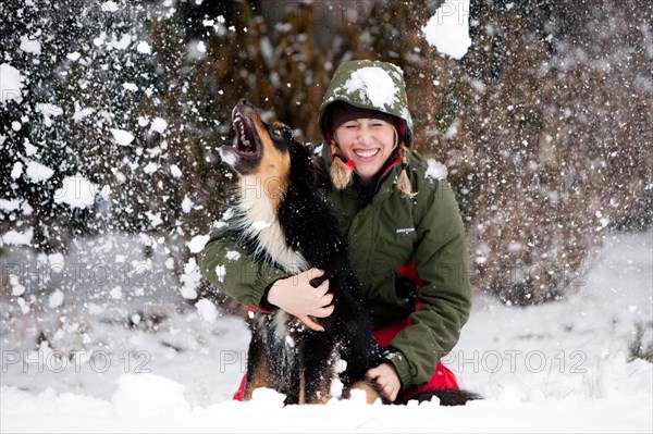 Young woman playing with an Australian Shepherd dog in the snow