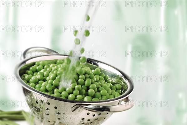 Garden peas and water splashing into a colander
