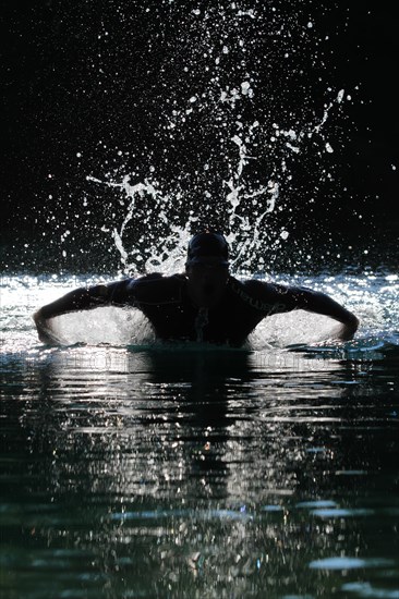 Man swimming with a butterfly stroke in a lake in Sonthofen