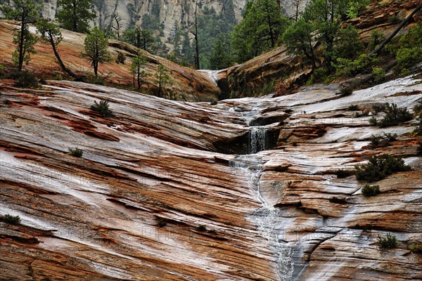 Water draining off over red Navajo sandstone rocks after a rainstorm near Canyon Overlook