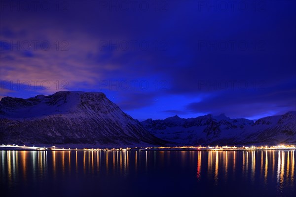 Reflection of lights in the fjord with mountains the blue hour