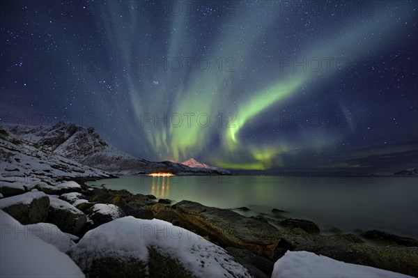 Aurora over fjord with snowy mountains