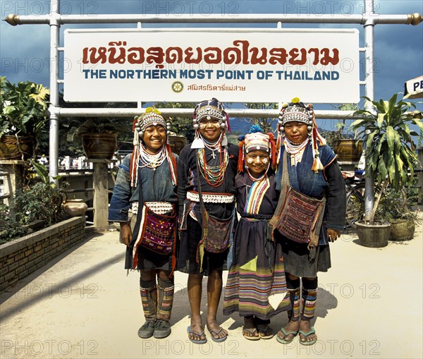Akha hill tribe girls wearing traditional costumes and headdresses standing at the northernmost point of Thailand