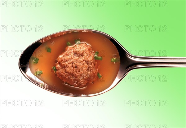 Meatball in broth on a silver spoon