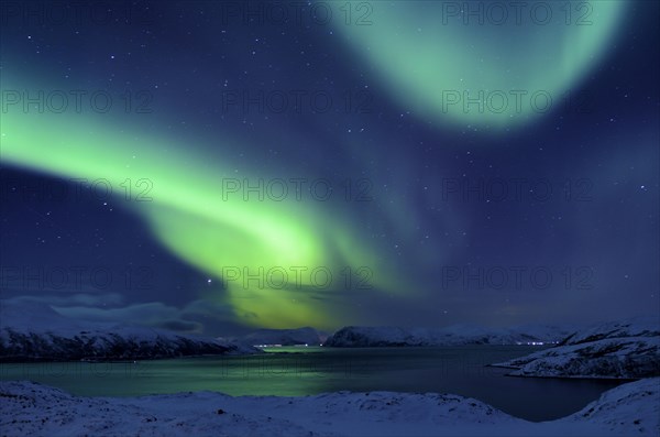 Northern Lights over fjord in winter landscape