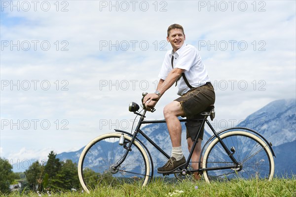Man wearing leather pants on an old bicycle