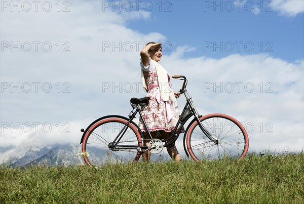 Woman wearing a dirndl with an old bicycle