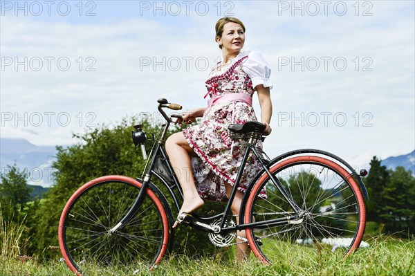 Woman wearing a dirndl on an old bicycle