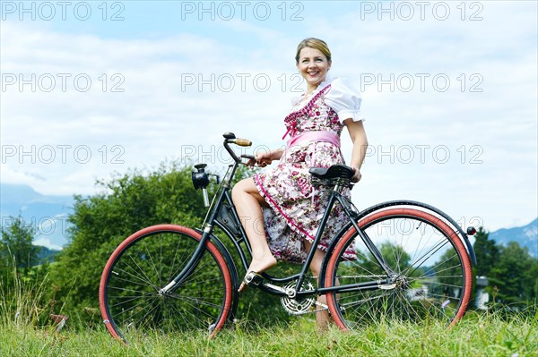Woman wearing a dirndl on an old bicycle