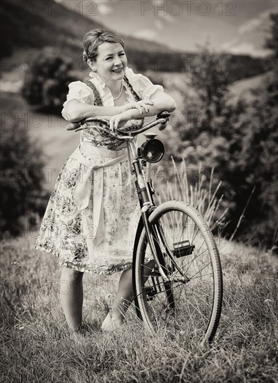 Woman wearing a dirndl with an old bicycle