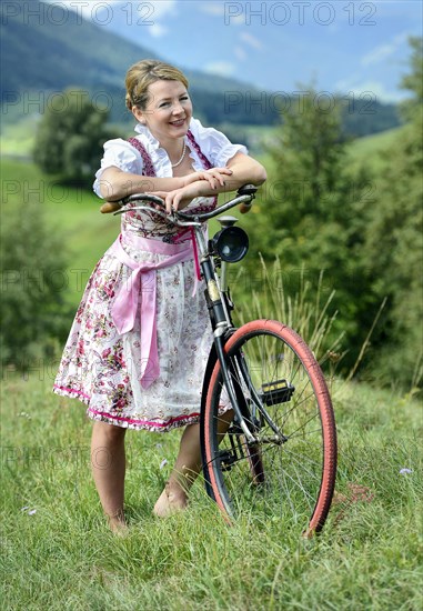 Woman wearing a dirndl with an old bicycle