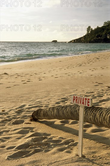 Deserted sandy beach with a wooden sign