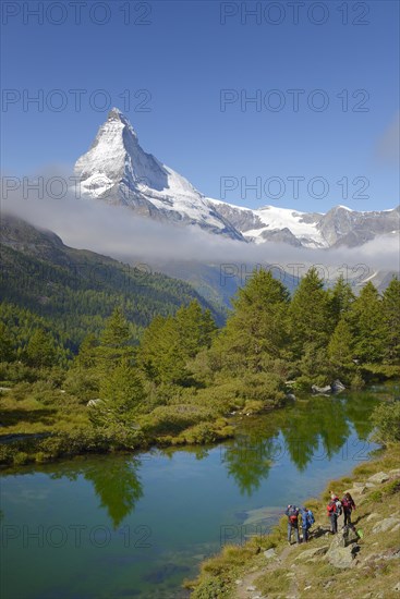 Hikers taking photographs of the Matterhorn with Lake Grindjisee in the foreground
