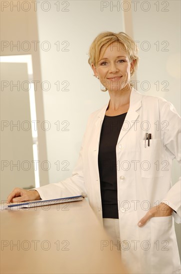 Female doctor in a white coat is standing at a reception desk