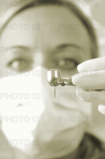 Dentist wearing a face mask and holding a drill