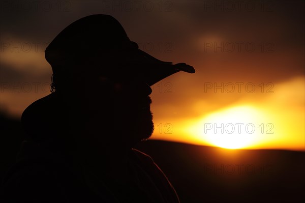 Silhouette of a cowboy in profile looking towards the sunset