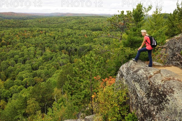 Female hiker standing on a rock overlooking woodlands