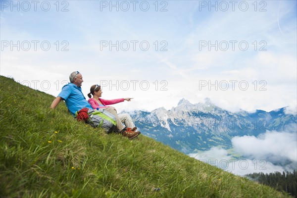 Hikers sitting on a mountain meadow and enjoying the view of the Tannheim mountains