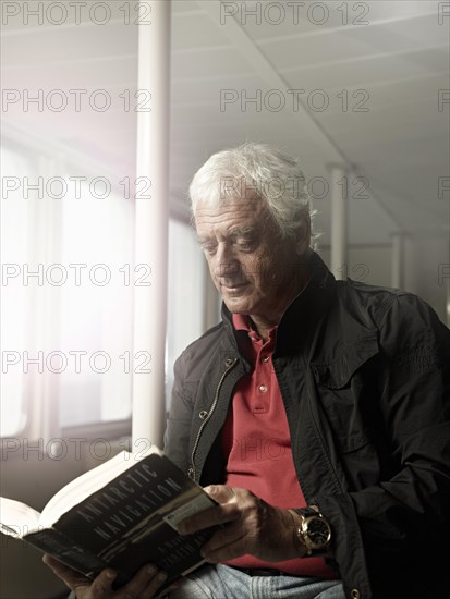 Elderly man reading a book on a ship