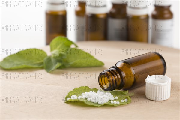 Open bottle with globules on a wooden board