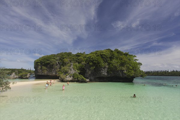 Tourists bathing in front of the sacred rock on the Ile des Pins