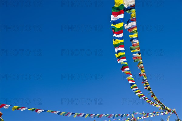 Buddhist prayer flags in front of blue sky above Namche Bazar (3.440 m)