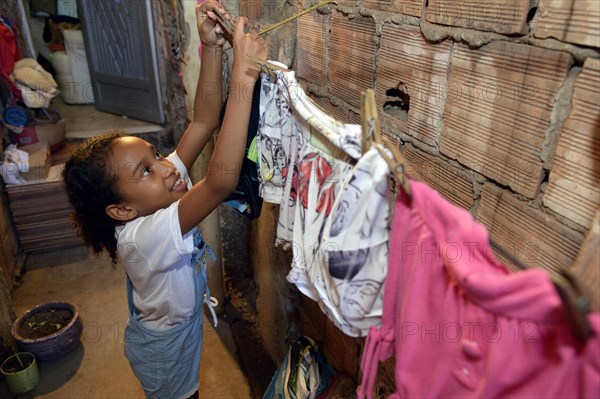 Girl hanging laundry on a clothesline in a slum or favela