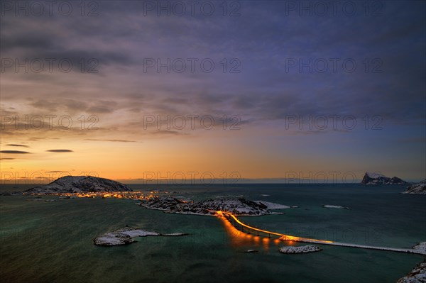 Fjord with an illuminated bridge in winter at sunset