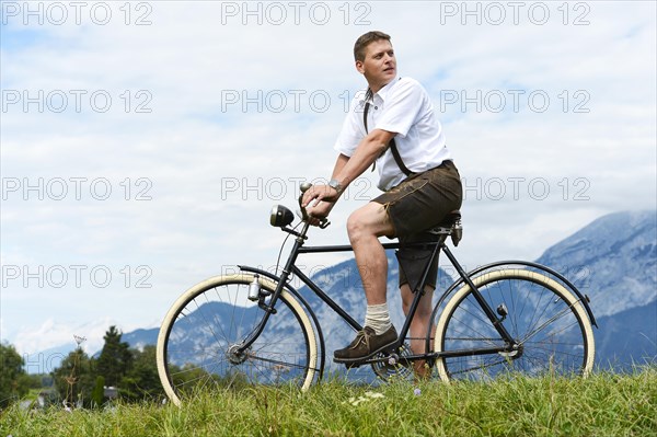 Man wearing leather pants on an old bicycle