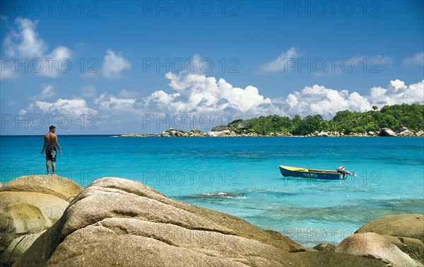 Rocky beach with a local fisherman and a fishing boat