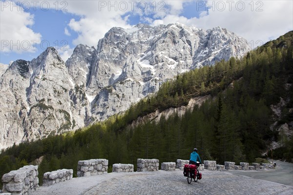 Cyclist in the mountain landscape near the Vrsic Pass with the 2547m high Prisojnik Mountain