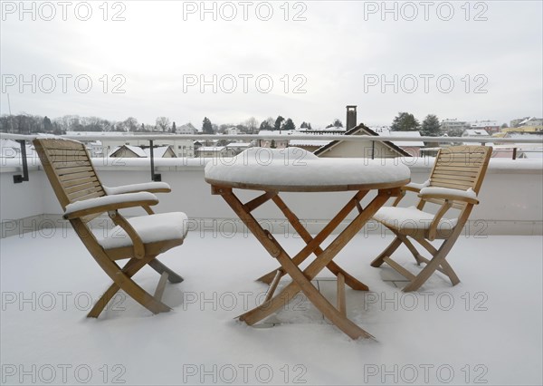 Two snow-covered chairs and a snow-covered table on a terrace