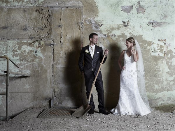 Bridal couple standing in front of a wall in an old industrial hall