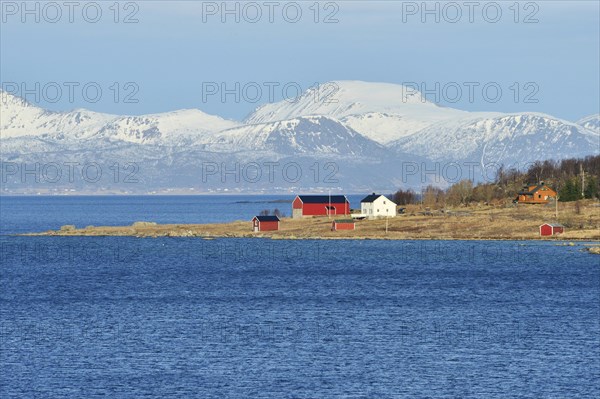 Headland with houses in the blue water of Hadselfjord and Raftsund