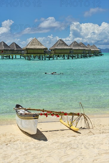 Decorated outrigger boat in front of overwater bungalows
