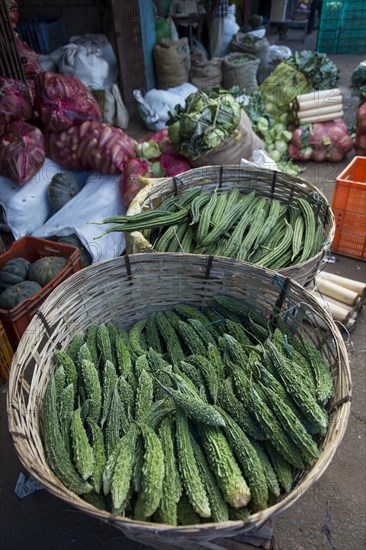 Bitter melons and cucumbers in woven baskets on the market