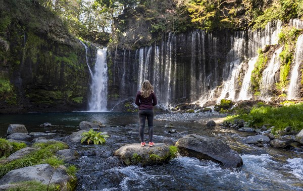 Young woman standing on a stone in a river