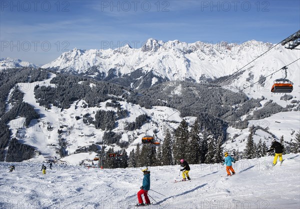 Skiers on slope in front of mountains