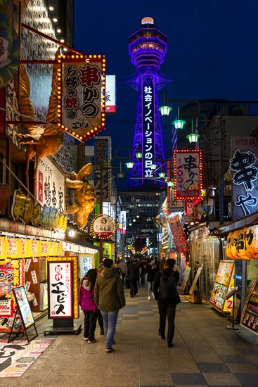 Many colorful neon signs in a pedestrian zone with shops and restaurants