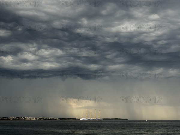 Five-master sailing ship in front of Crveni Vrh in thunderstorm atmosphere seen from Piran