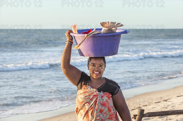 Malagasy woman carrying fish in a tub on her head