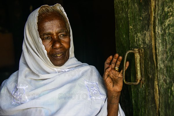 Friendly old woman standing in a door frame near Keren