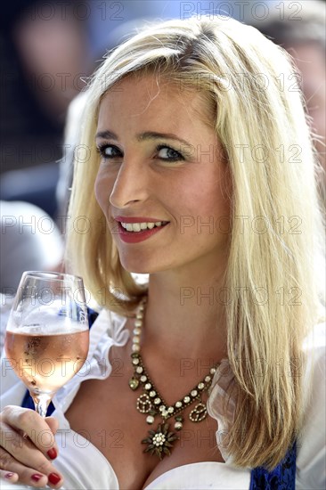 Young woman wearing a dirndl dress holding a wine glass