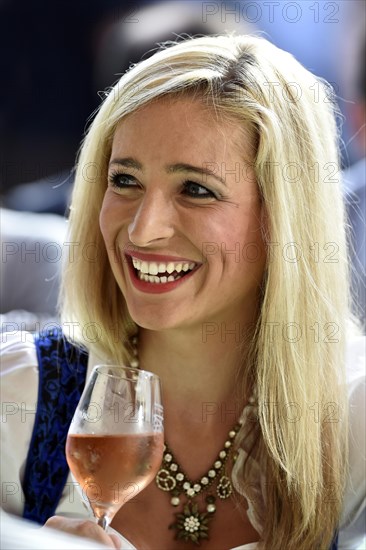 Young woman wearing a dirndl dress holding a wine glass
