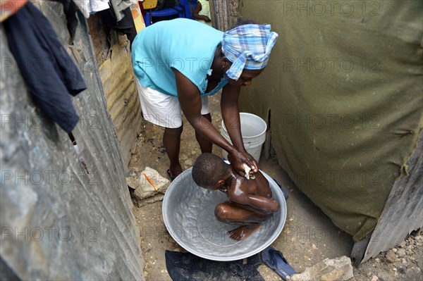 Woman washing a boy outside her hut