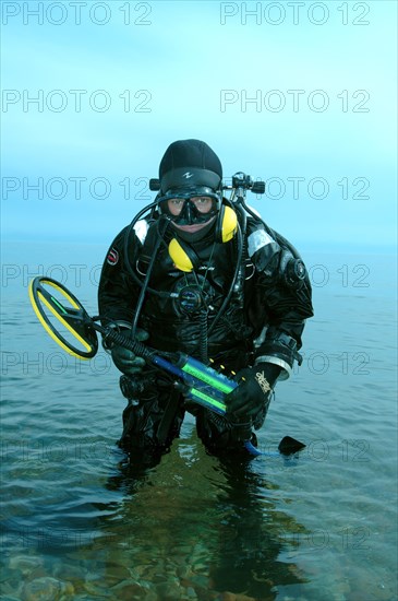 Diver with metal detector searching for underwater treasure