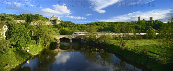 Ruins of Rudelsburg Castle and Burg Saaleck Castle on the Saale River with an ICE train crossing a railway bridge